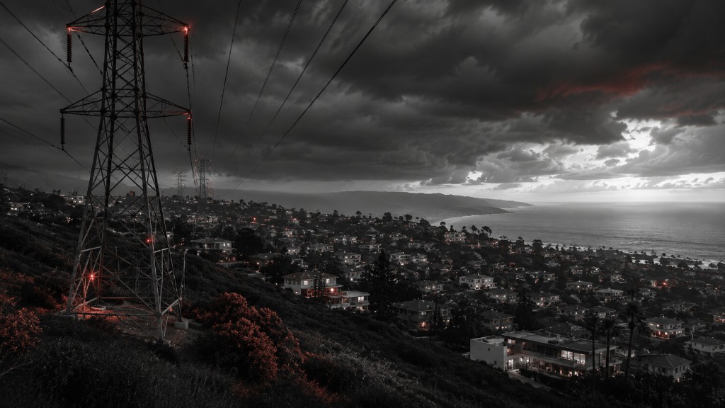 High-voltage transmission tower on a hillside overlooking a coastal town at dusk, with red warning lights on the structure.