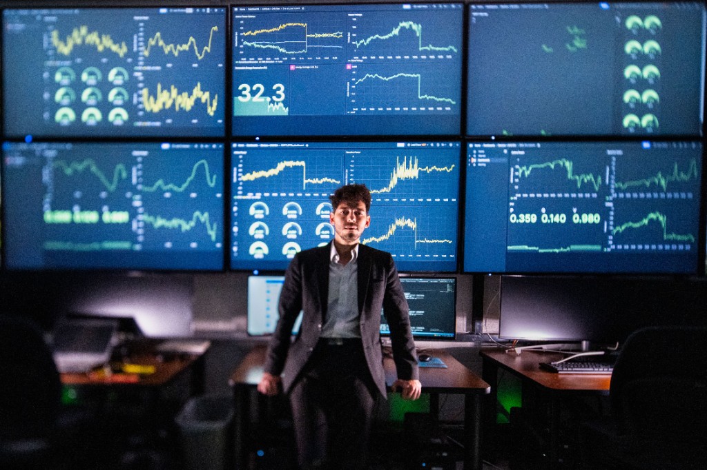 Operator monitoring grid telemetry on a multi-screen control wall